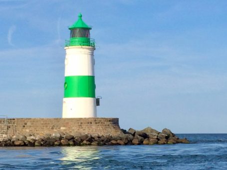 Leuchtturm Schleimünde Grün weißer Leuchtturm Schleimünde vor blauem Himmel und Spiegelung im Meer.