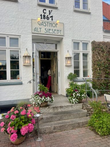 Gasthaus Alt Sieseby Weißes Backsteinhaus mit Sprossenfenstern und Türbeschriftung Gasthof Alt Sieseby.